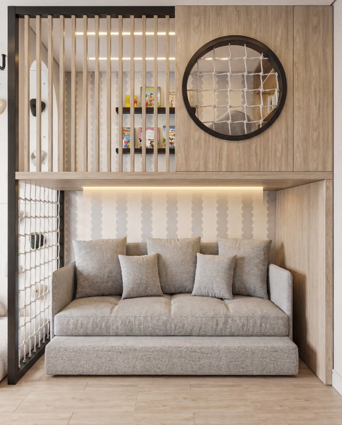 A reading nook set into pale wood: a grey sofa under a lit alcove, a knotted rope net to one side, and a loft above it behind vertical slats, with picture books face out on low shelves and a round black framed window.