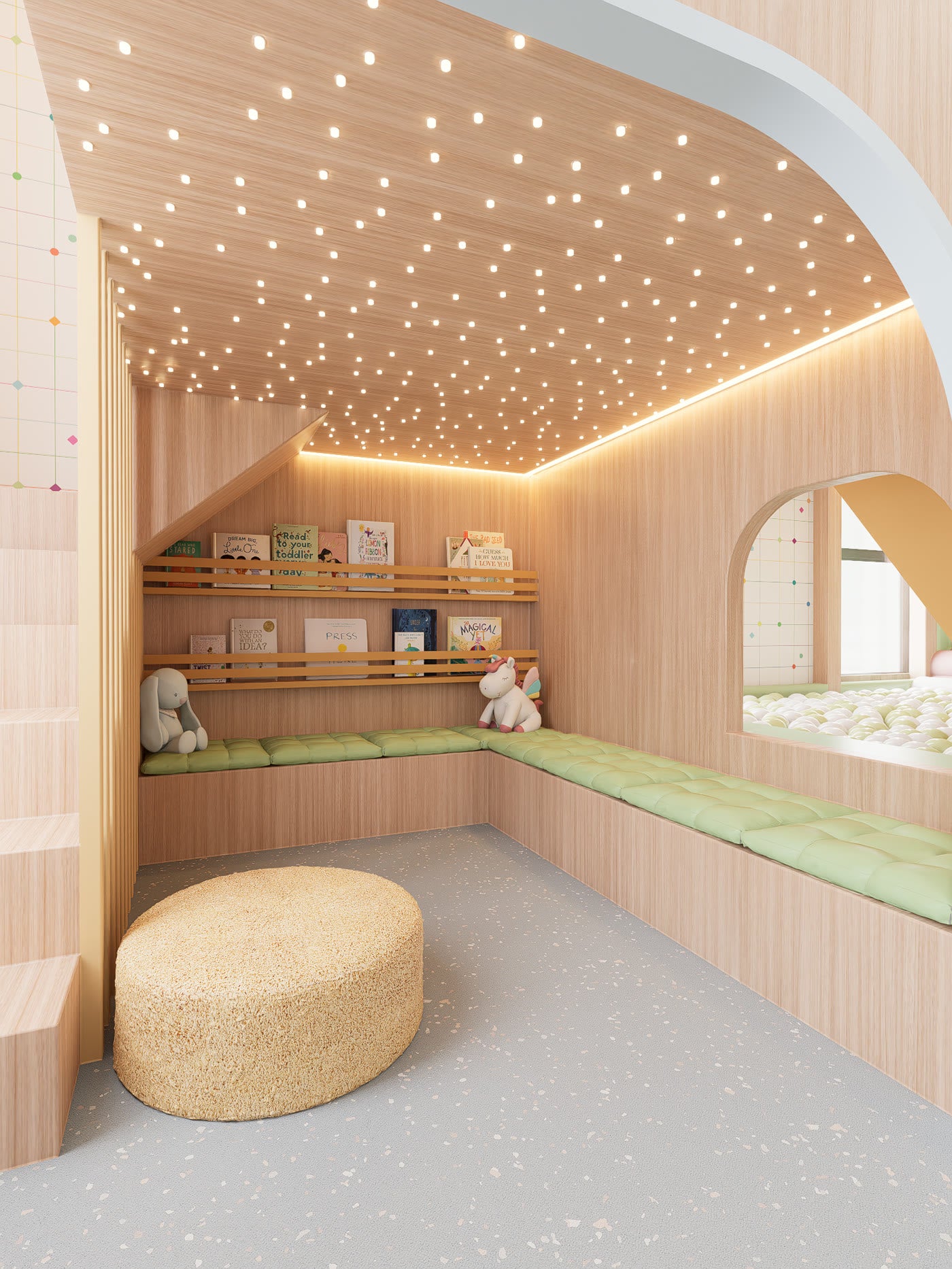 A reading nook under the play structure at Lyfe Playhouse: benches with green cushions on two sides, a book rail with picture books, a star ceiling of small lights, and a window through to the ball pit.